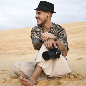Bambú de All These Humans sonría con su cámara fotográfica en el desierto