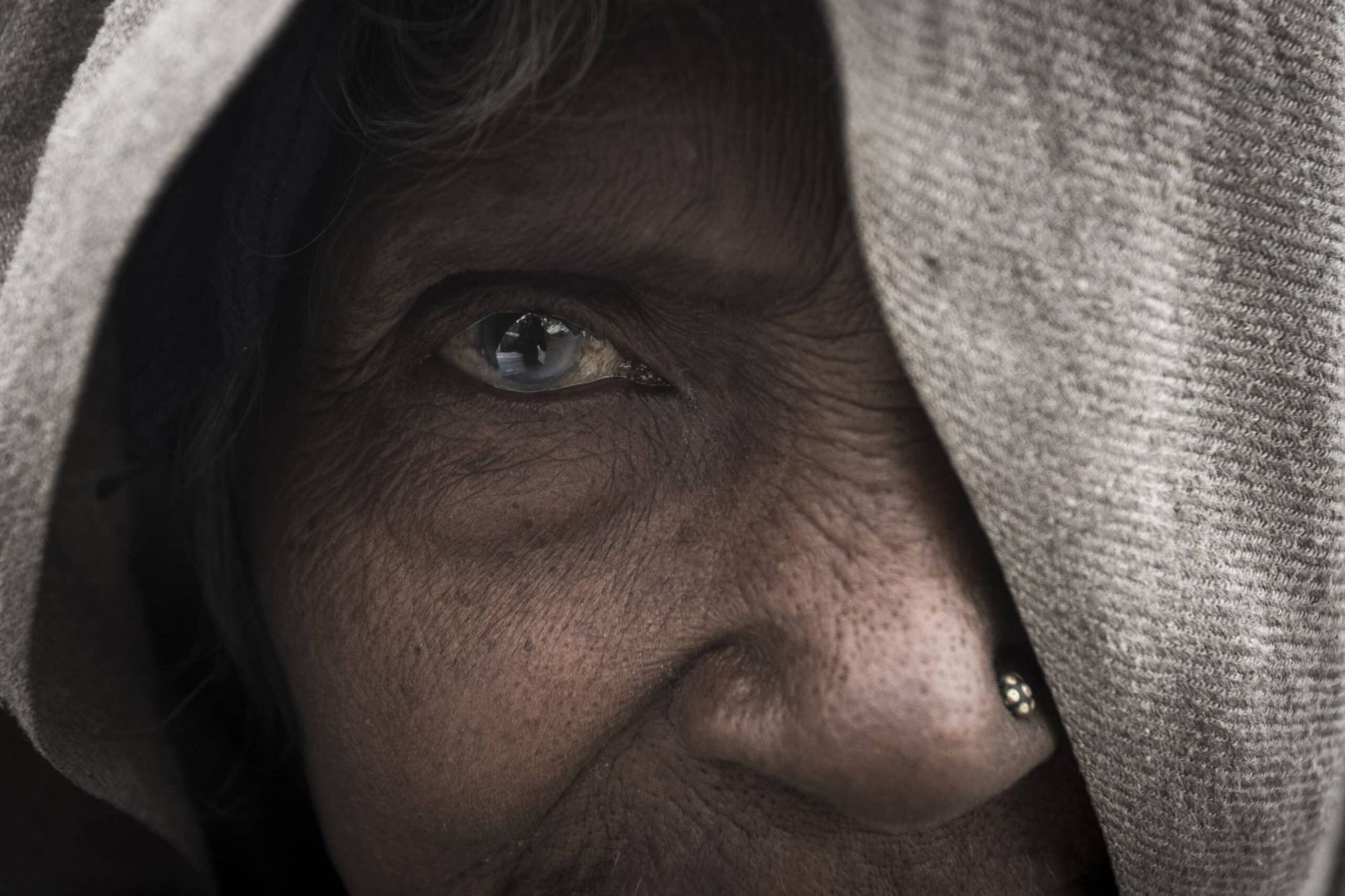 fotografía artística de retrato a color del ojo azul profundo de una mujer con capucha en primerísimo primer plano