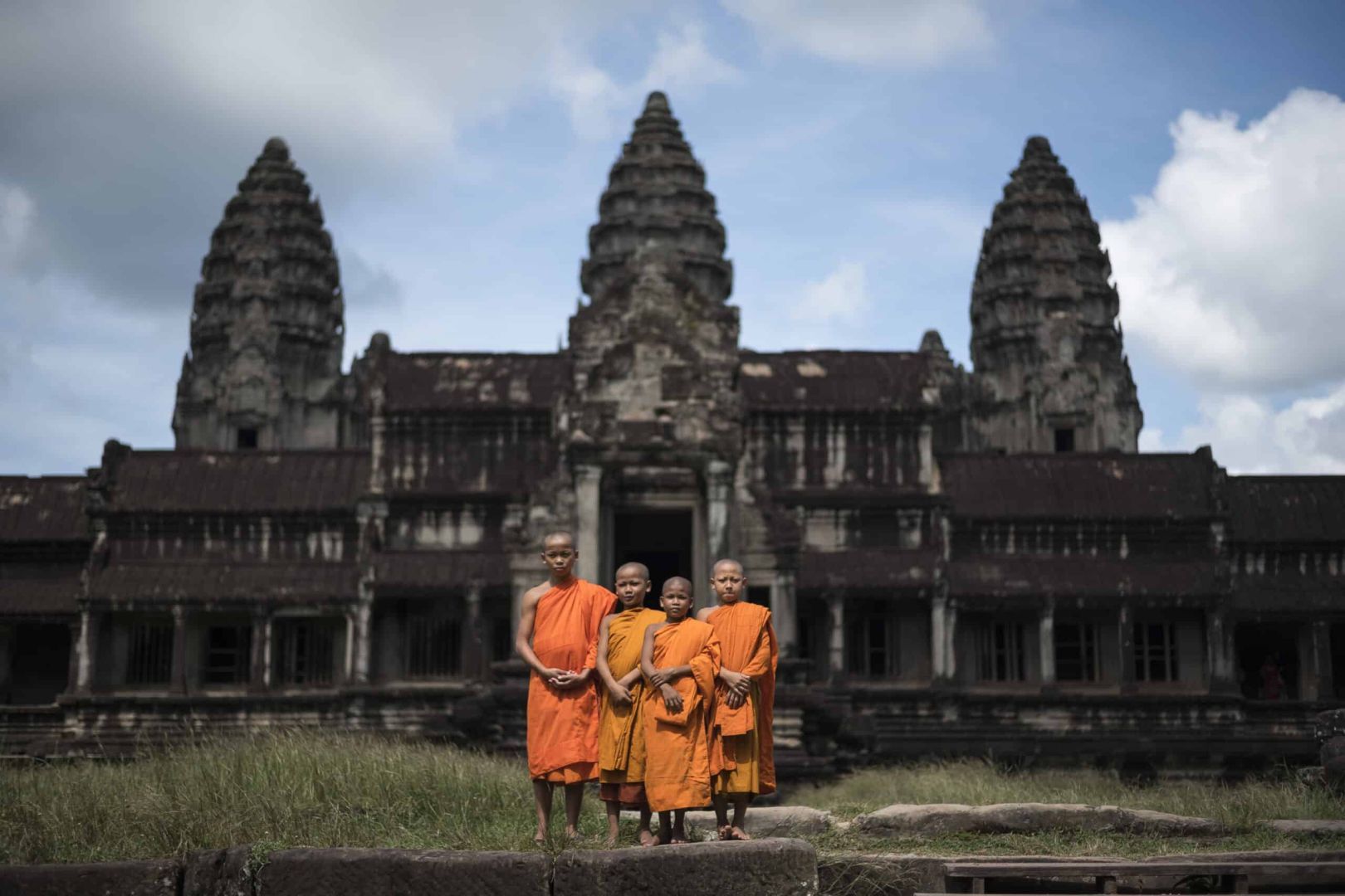 fotografía artística en blanco y negro de cuatro niños monjes budistas de camboya junto al templo de angkor wat
